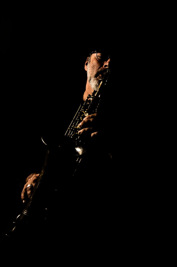 Moody portrait of a saxophone musician playing in a dark setting.