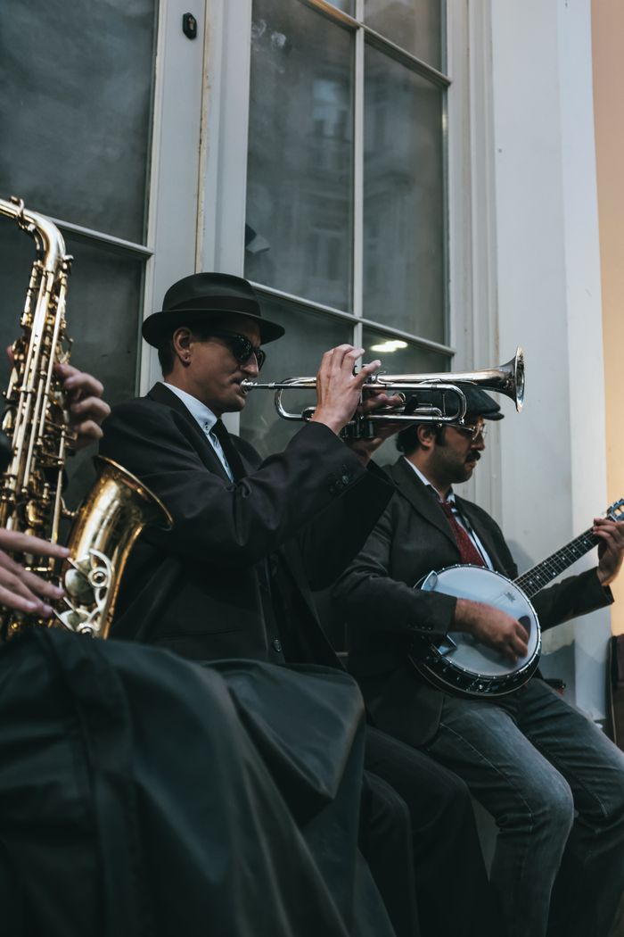 Mastering the First Impression: Your intriguing post title goes here A jazz band in suits playing wind and string instruments on a city street.
