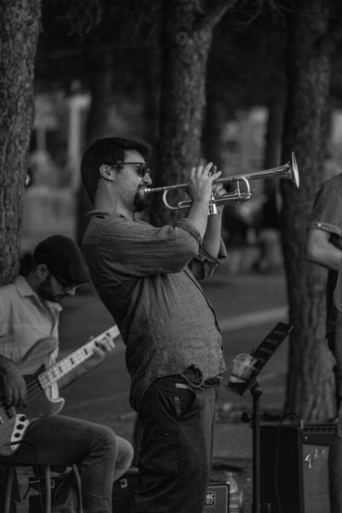Black and white photo of a street musician passionately playing the trumpet.